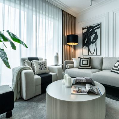 bardzo nowoczesny salon w stylu glamour, dużo dekoracji typu poduszki, koce, lampy, obrazy), zasłony i firany w oknie